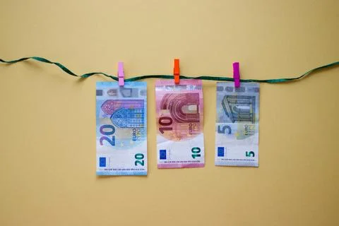 Euro banknotes hanging on string with clips on yellow background Stock-Fotos