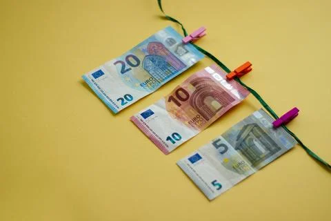 Euro banknotes hanging on string with clips on yellow background Stock Photos