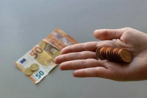 Euro coins in hand.Banknote and more coins on grey  background. Stock Photos