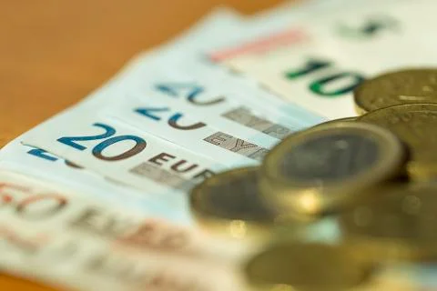 Euro notes and coins strewn across a table with very shallow focus Stock Photos