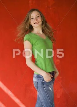 Europe, Teenage girl turning back with red wall in background, smiling, portrait Stock Photos