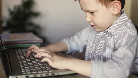 A European boy is learning to type on a laptop. Online school. Distance learning Stock Footage 167599954