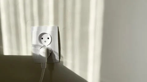 European electrical wall outlet powers connected white plug catching morning sun 스톡 동영상 333691202
