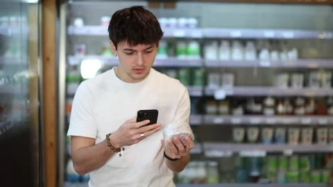 European guy scans a mobile barcode of a cheese package in an eco supermarket Stock Footage 311839639