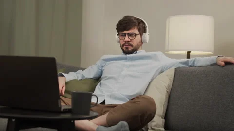 A European man with headphones is watching a movie on his laptop. Stock Footage