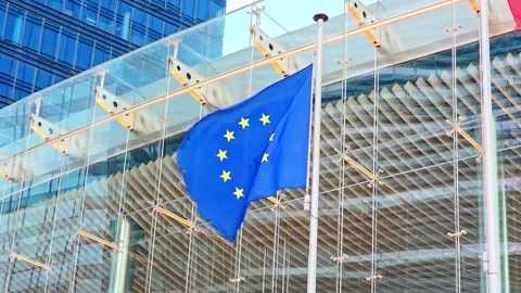 European Union flag waves in the wind against a glass office building facade. Vídeo Stock 340926361