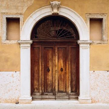 European vintage wooden door with white stone arch columns. Building facade Stock Photos
