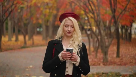European Woman Smiling While Using Her Phone in Forest Park Stock Footage 296144394
