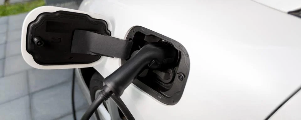 EV car plugged-in with cable from progressive home charging station. Stock Photos
