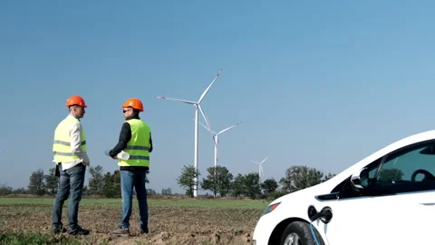 EV charged by energy engineers stand against windmills 库存影片 164276848