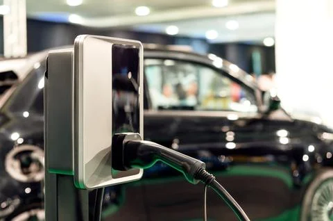 EV charging plug on background of blurred black car Stock Photos