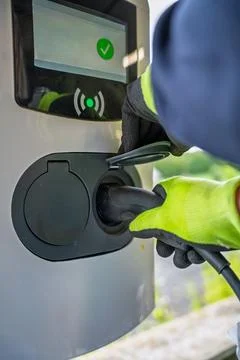 EV Close-up of hands connecting cables to an electric vehicle charger Stock Photos