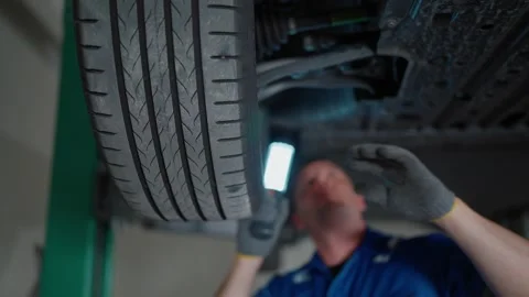 EV Mechanic examines undercarriage with focused intensity Video stock 338332443