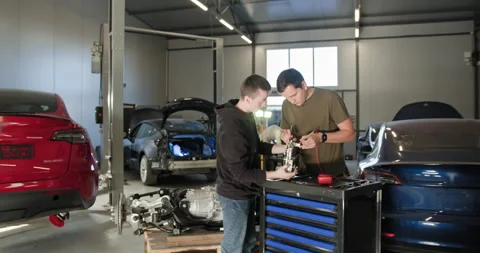 EV repair concept. Auto Service. Two male mechanics working together on an Stock Footage 277341804