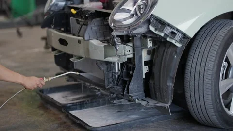 EV Technician cleans car's front bumper with compressed air Видео 339050376
