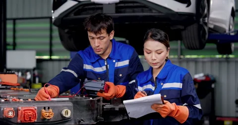 EV technician teamwork with male and female mechanics testing exposed high Stock Footage 345517718