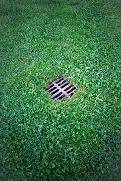 Evacuation grate in the grass of the park Stock Photos