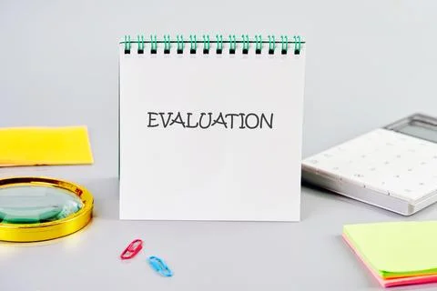 EVALUATION word written in a notebook in a composition with a calculator, a Stock Photos