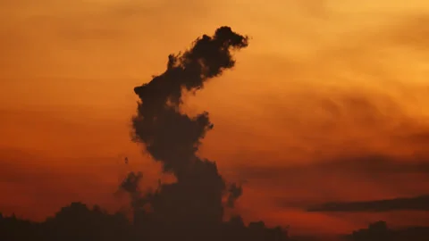 Evaporating dark cloud time lapse, silhouette dissolving into vibrant sunset sky Stock Footage 346312625