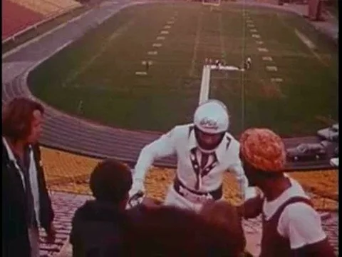 Evel Knievel performs an impressive stunt jump over a line of cars while Peter Stock Footage 75275692