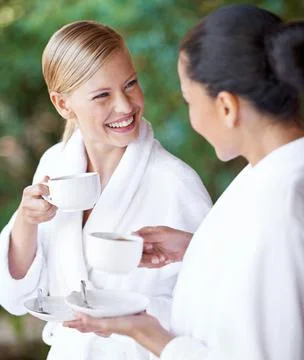 Even the coffee is relaxing. Two young women having coffee in their bathrobes at Stock Photos