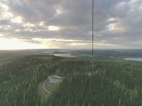 Evening aerial view of 327 meter high transmission tower on dense forest Stock Footage 76817564