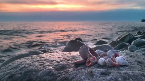 Evening beach at sunset with waves of stones shell rays of the sun Stockbeeldmateriaal 151747176