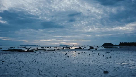 Evening beautiful tropical beach at low tide with scattered stones. The camera Stock Footage 250132811
