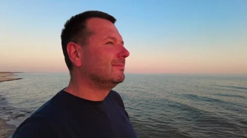 Evening Bliss: Man Watching the Sun Set Over the Ocean Video stock 282774437