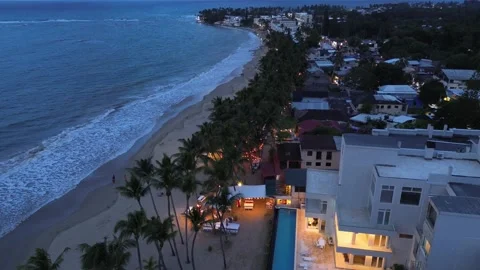Evening Cabarete Beach with Palm Trees and Illuminated Restaurants. Aerial View Stock Footage 314866465