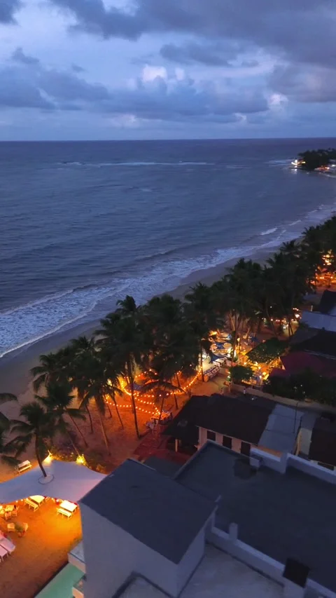 Evening Cabarete Beach with Palm Trees and Illuminated Restaurants. Aerial View Stock Footage 314866743