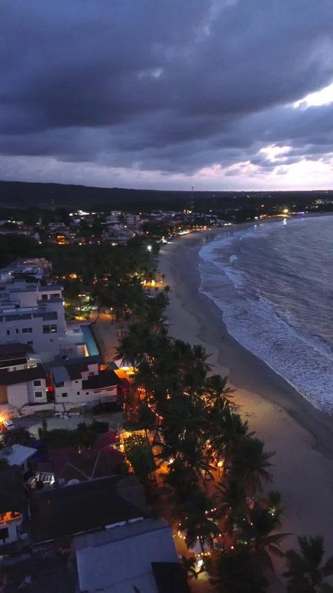 Evening Cabarete Beach with Palm Trees and Illuminated Restaurants. Aerial View Stock Footage 314866780