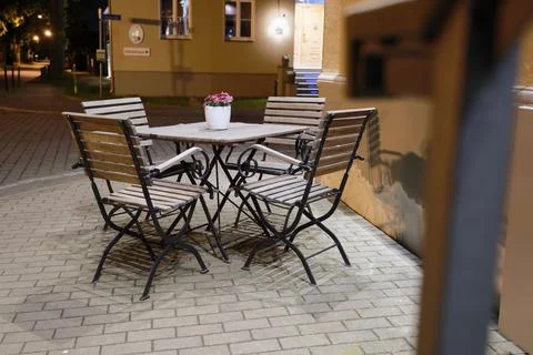 Evening city corner with a table four chairs and flowers Stock Photos