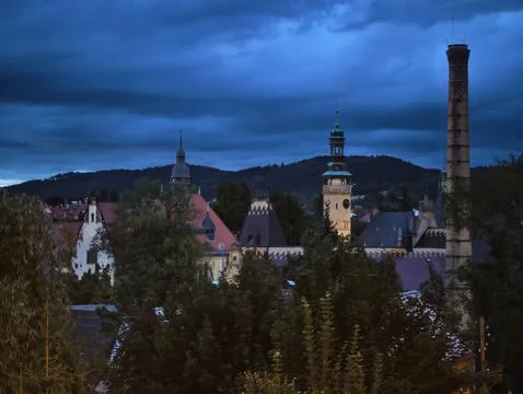 Evening cityscape with clocktower, steeple, and distant hills beneath blueh.. 스톡 사진
