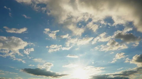 Evening clouds moving with sun shining on blue sky Stock Footage 142703164
