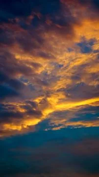 An evening cloudy sky view with the yellowish orange sunlight peeps through t Stock Photos