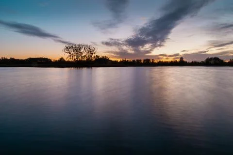 Evening colourful clouds after sunset over a calm lake Stock Photos