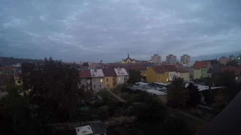 Evening coming with moon sunset behind clouds over roofs of small town Video stock 56473936
