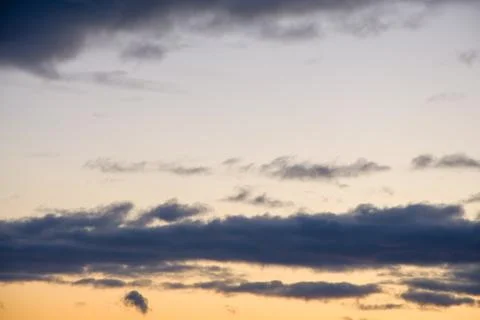 Evening dark clouds against the setting sun, yellow reflections on the horizon. 写真素材