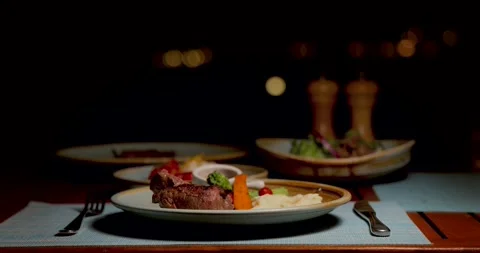 Evening dining table with steak, mashed potatoes, vegetables. Cozy Stock Footage 312000942