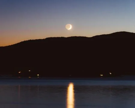 Evening forest scenery in shadow with moon on sky while sunset Foto stock