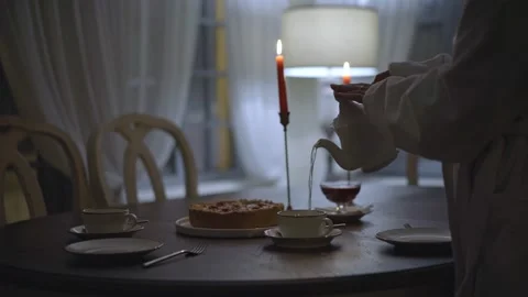 Evening a girl pours tea on the table cake and candles Stock Footage 232714223