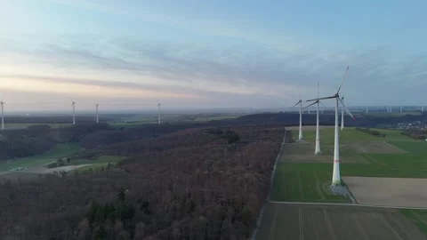 Evening glide beside forest toward distant wind turbines Stock Footage 331215243
