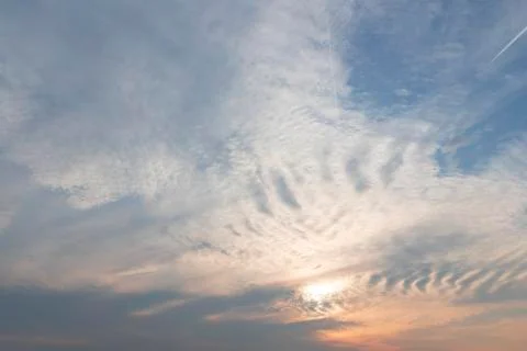 Evening haze, wavy white clouds, pink glow of sunset. Beautiful cloudscape Stock Photos