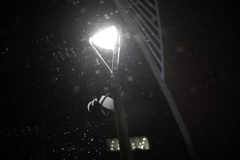 Evening. It's snowing in the light of a lantern Stock Photos