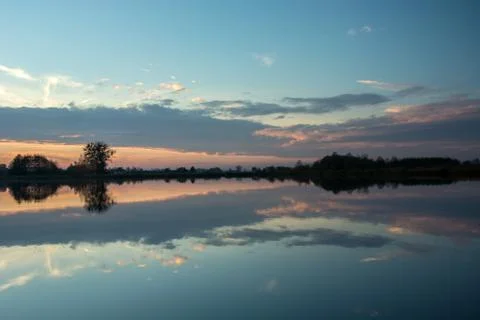 Evening at the lake and reflection of clouds after sunset in the water Stock Photos