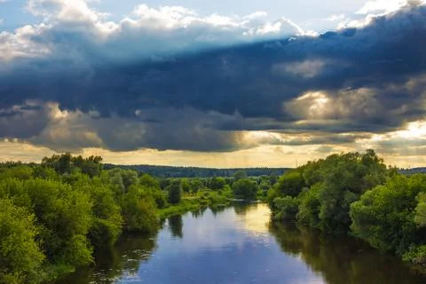 Evening landscape with dramatic sky with clouds and river Stock Photos