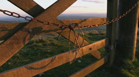 Evening light highlights a chain swinging on a gate in the countryside. Stock-Footage 63200164