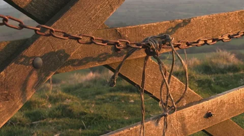 Evening light highlights a chain swinging on a gate in the countryside. Stock Footage 63202682