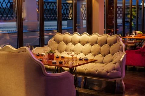 Evening lounge nook with tufted settee and polished table setting Stock Photos